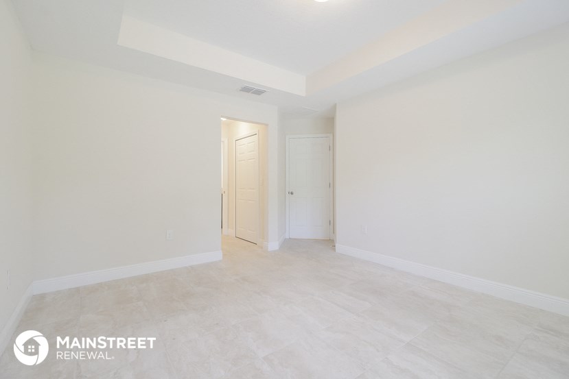 the living room and dining room with white walls and tile flooring