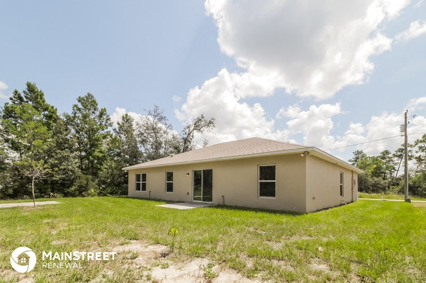 the view of the house from the backyard with grass and trees