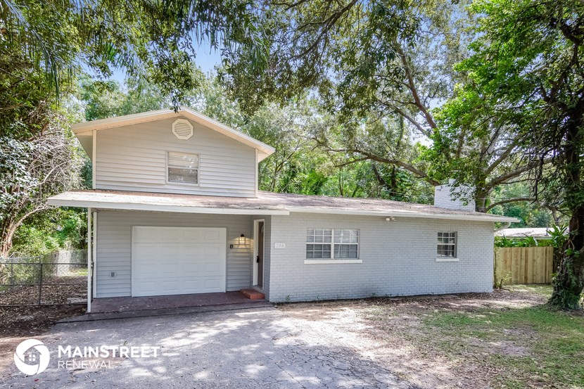 a small white house with a garage and some trees