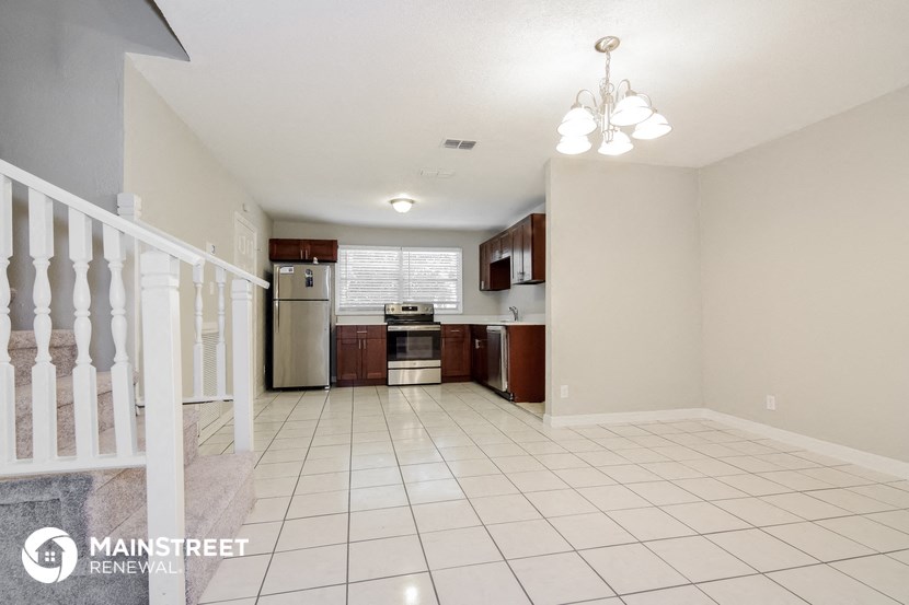 a large kitchen with white tile flooring and a staircase