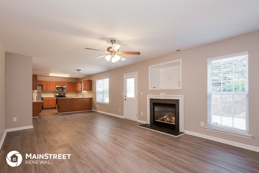 an empty living room with a fireplace and a ceiling fan
