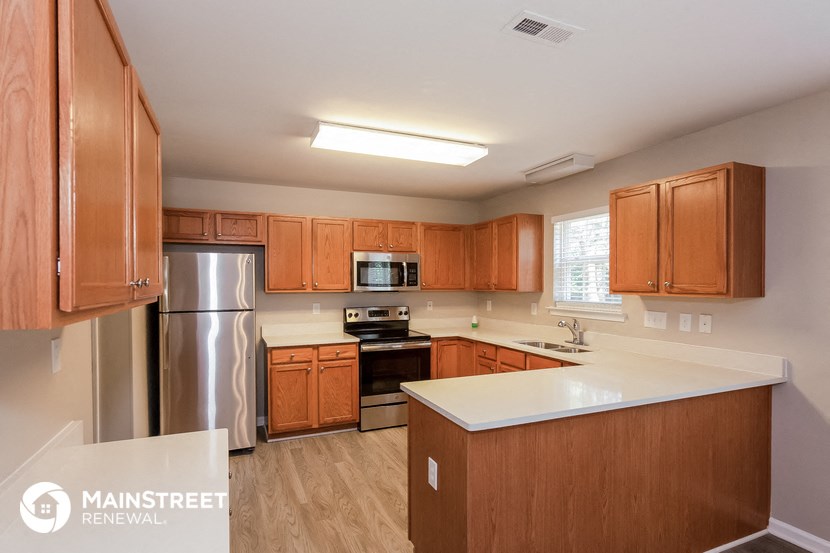 a kitchen with wooden cabinets and stainless steel appliances and a white counter top