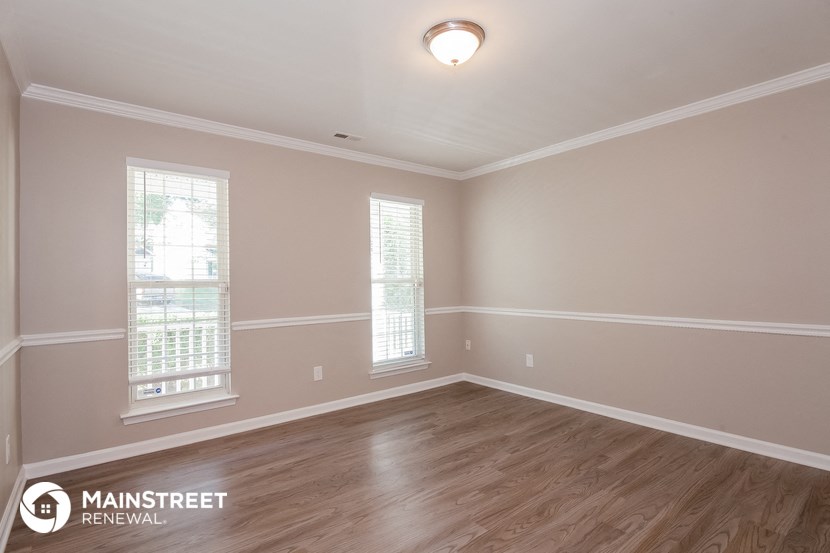 the spacious living room with hardwood flooring and two windows