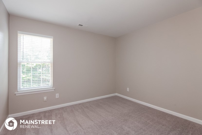 a bedroom with a carpeted floor and a window