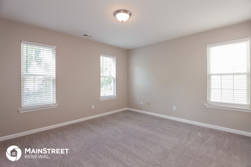 the upstairs bedroom with carpet and three windows