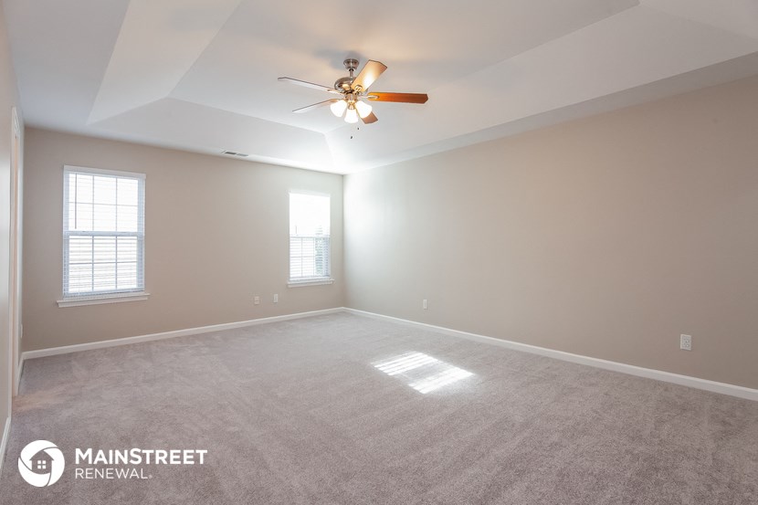 the spacious living room with carpet and ceiling fan