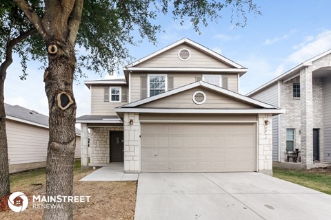 a white house with a garage door and a tree