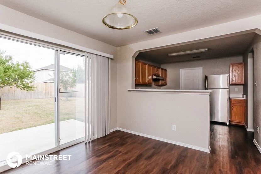 an empty living room with a kitchen and a sliding glass door