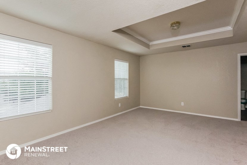 the spacious living room of a home with a large window