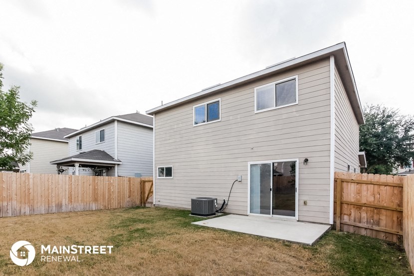 the exterior of a white house with a yard and a wooden fence