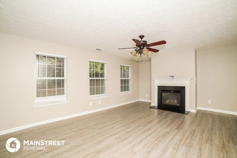 a living room with a fireplace and a ceiling fan