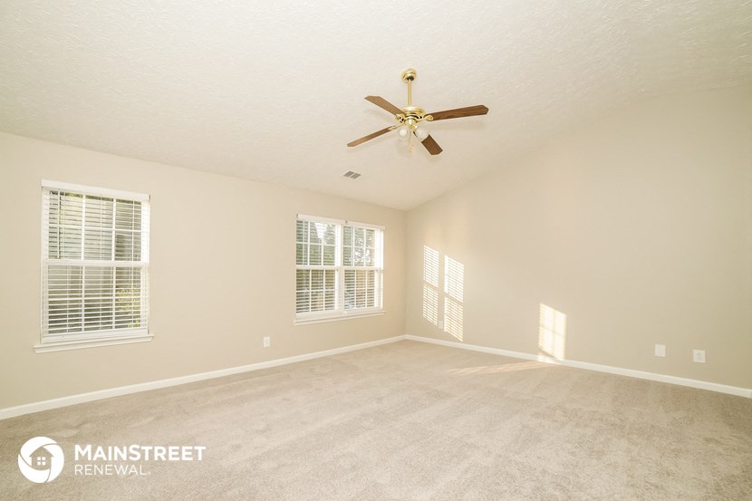 a spacious living room with carpet and a ceiling fan