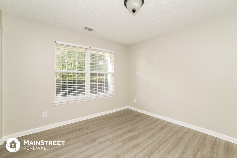 the living room of a new home with wood flooring and a window