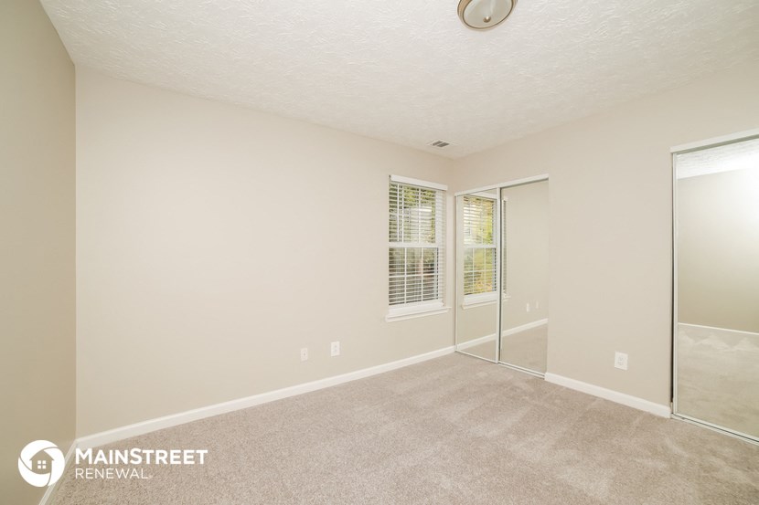 a living room with a mirrored closet and a carpeted floor