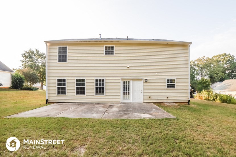 the front of a small white house with a concrete driveway
