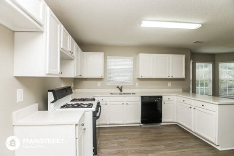 a white kitchen with white cabinets and black appliances