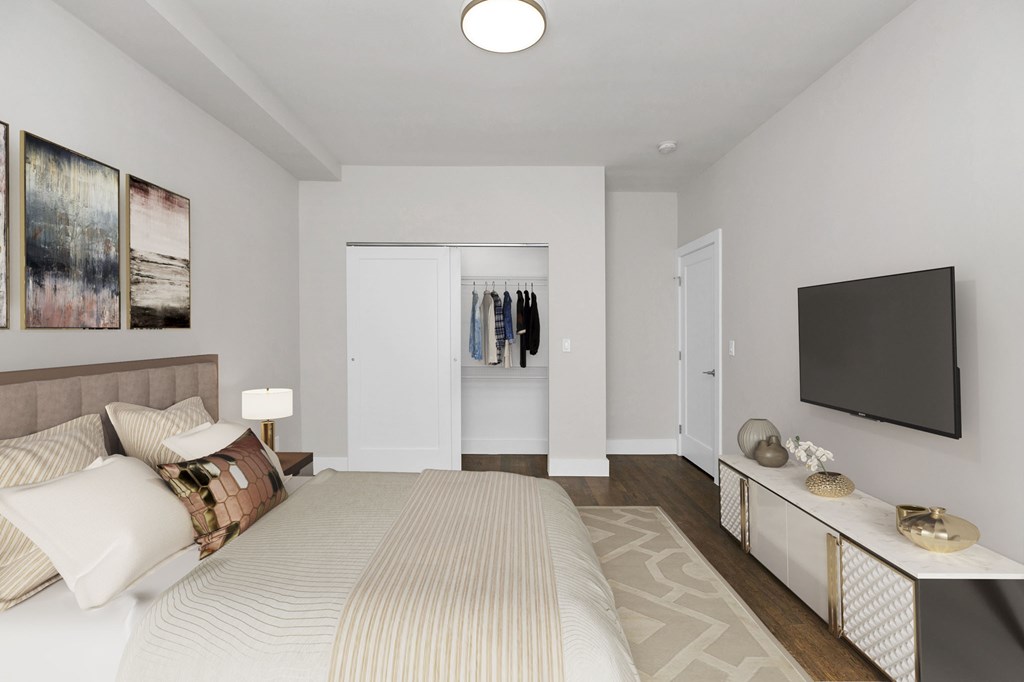 A bedroom with a large bed and a TV on the wall.