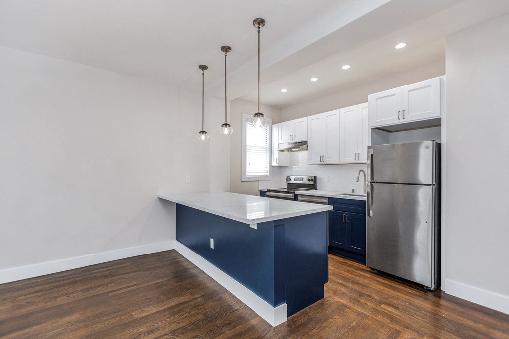 A kitchen with a blue island and stainless steel appliances.