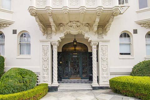 A white building with a black door and a decorative archway above it.