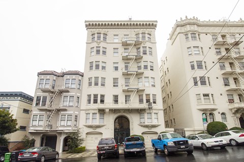 A row of old buildings with cars parked in front.