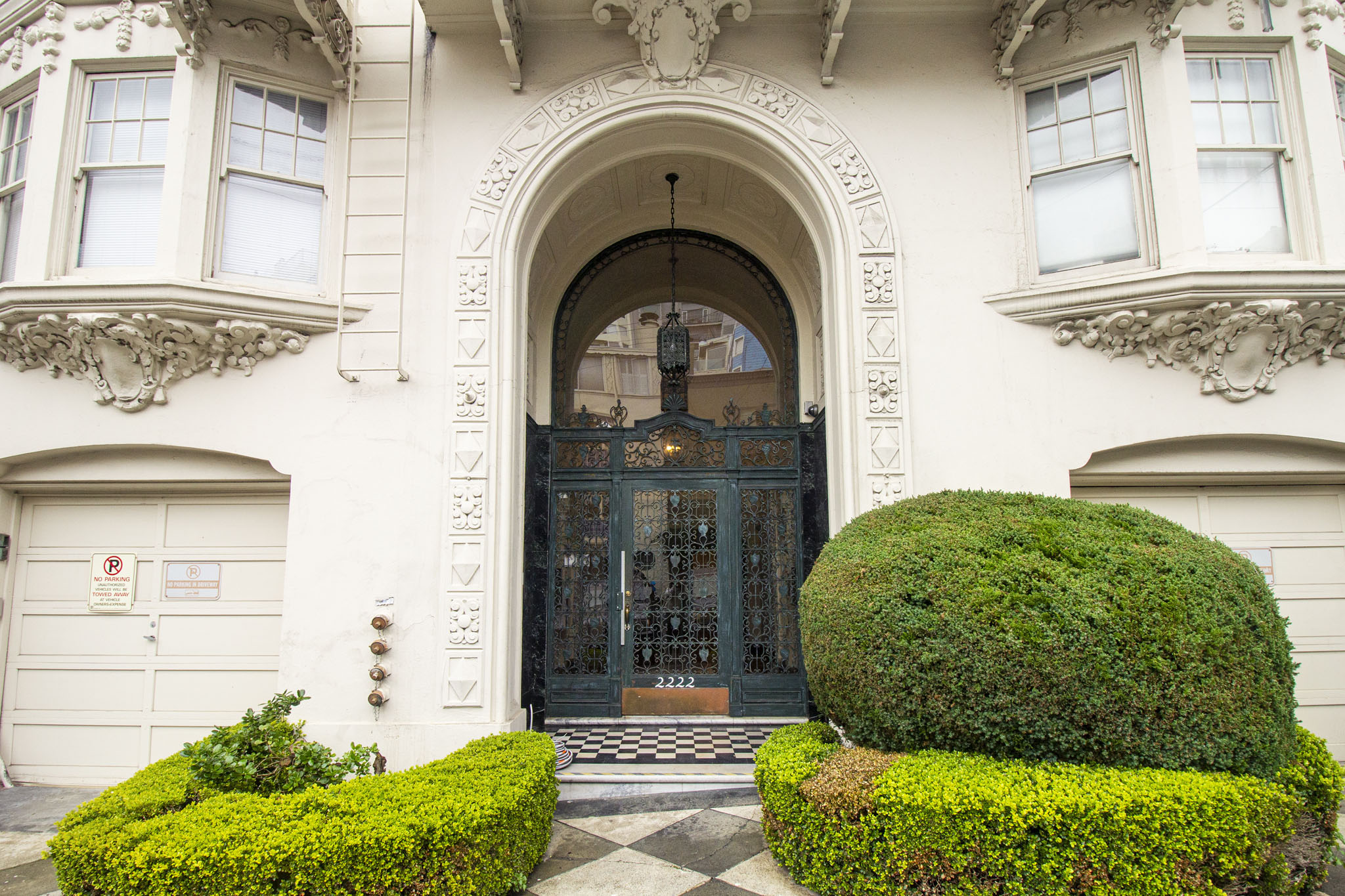 A large, ornate entrance to a building with a black door and a sign on the wall.