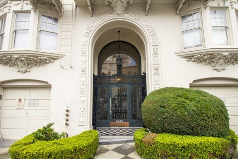 A large, ornate entrance to a building with a black door and a sign on the wall.