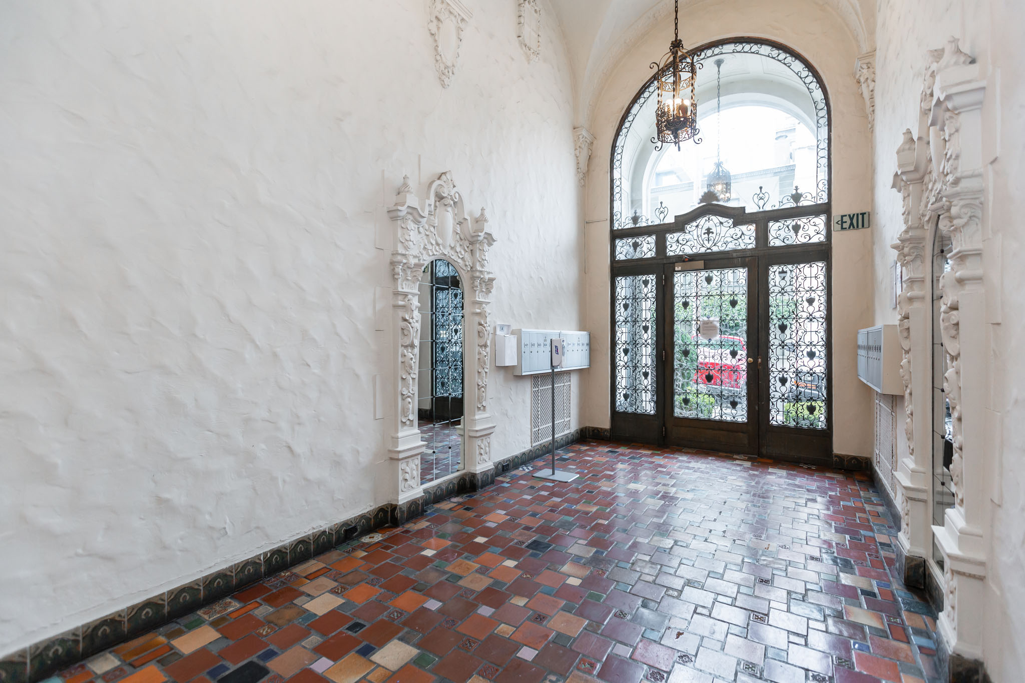 A hallway with a tiled floor and a large arched doorway with an "EXIT" sign above it.