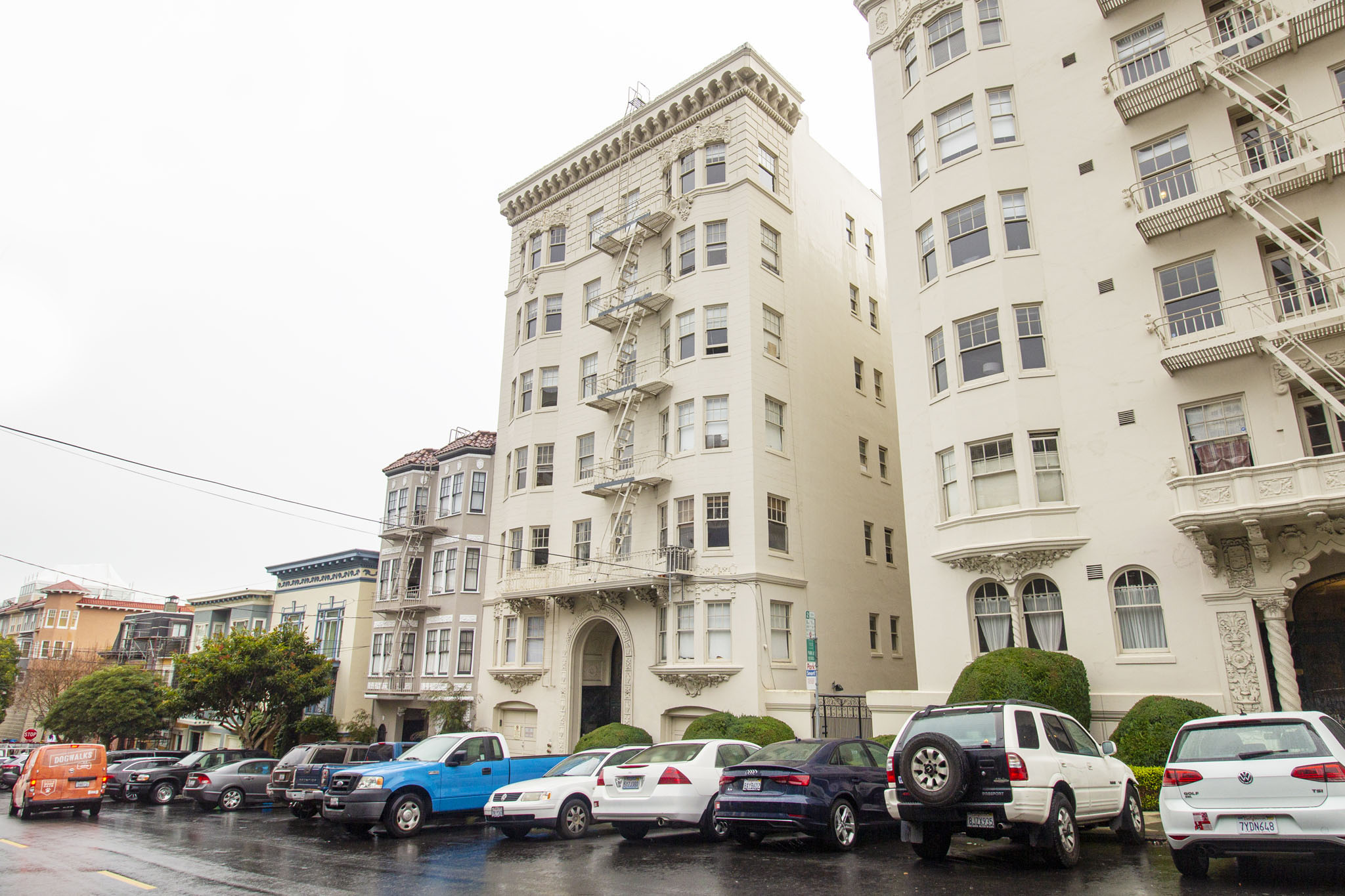 A row of cars are parked in front of a building.