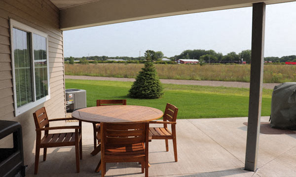 a patio with a table and chairs and a view of a field