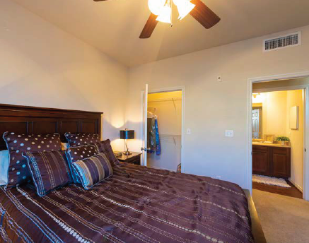 A bedroom with a large bed and a ceiling fan.