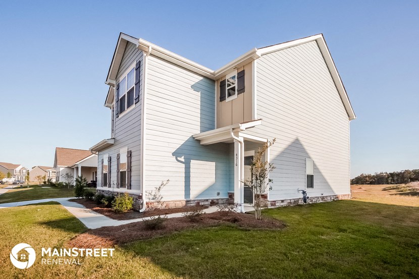a white and blue house with a sidewalk in front of it