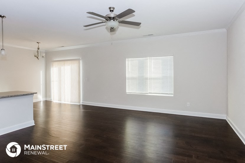 an empty living room with wood floors and a ceiling fan