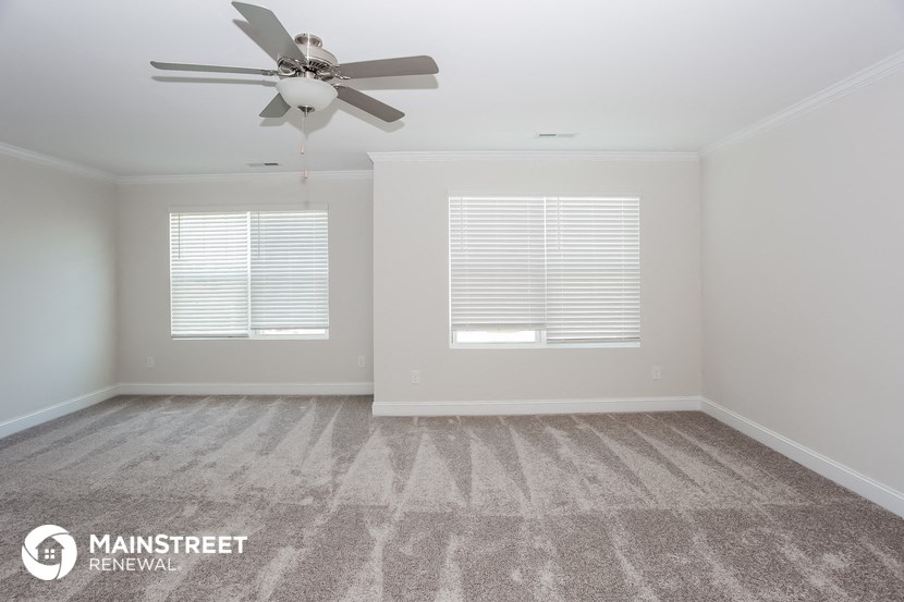 the spacious living room with carpeting and a ceiling fan