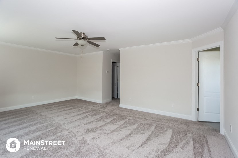a spacious living room with carpet and a ceiling fan