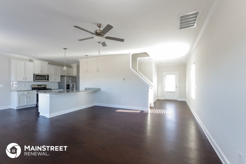 an empty living room and kitchen with white walls and a ceiling fan