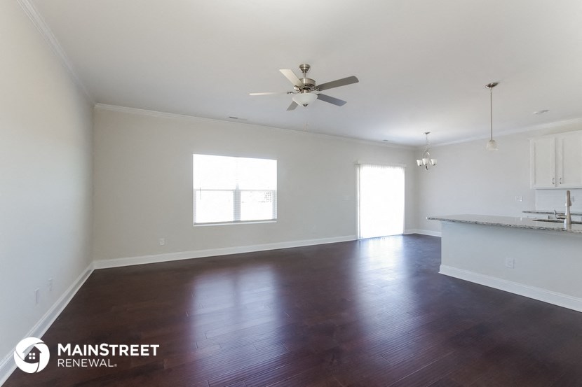 an empty living room with wood floors and a ceiling fan