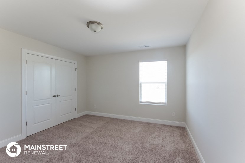 a bedroom with white walls and a white door and a window