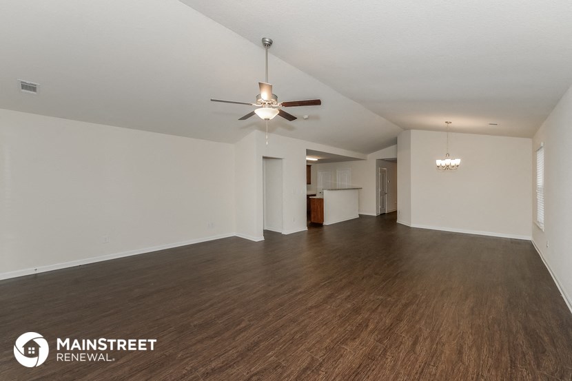 an empty living room with a ceiling fan and wood flooring