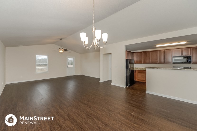 the living room and kitchen of an open floor plan with wood flooring