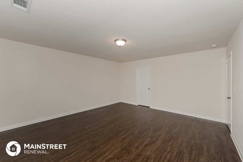 the spacious living room with wood flooring and white walls