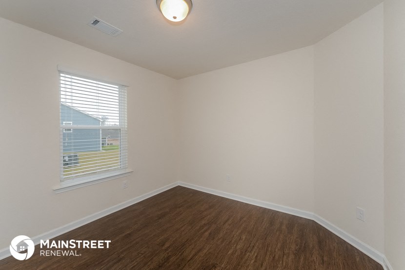 the interior of an empty room with wood flooring and a window
