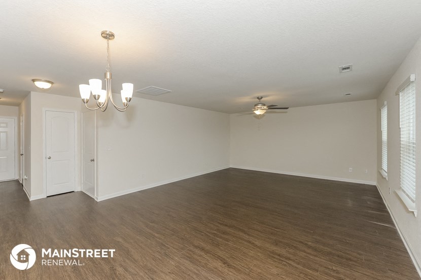 the living room of an apartment with a wood floor and a ceiling fan