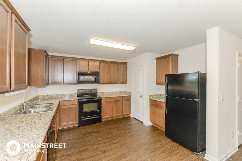 a kitchen with wooden cabinets and a black refrigerator