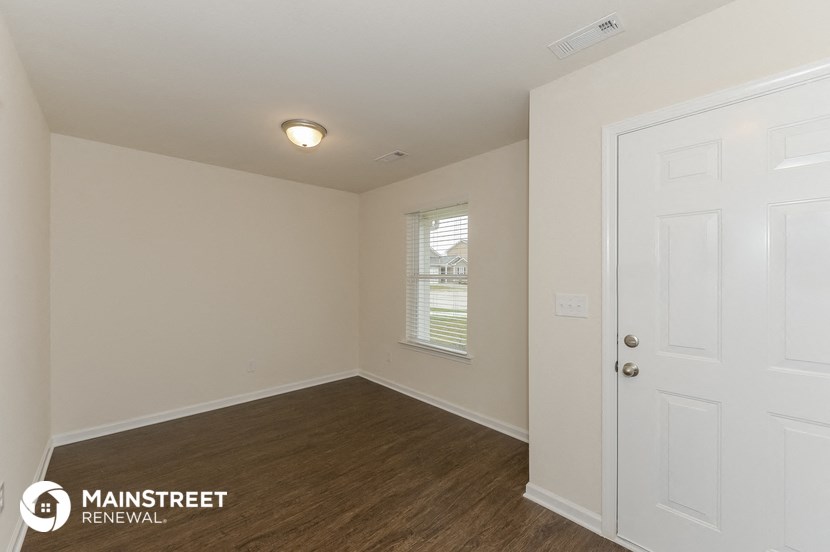 the living room of a small white house with wood flooring and a white door