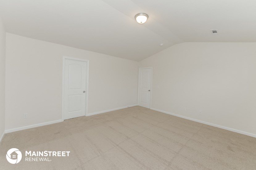 the spacious living room with white walls and wood flooring