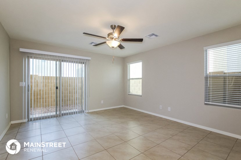 an empty living room with a ceiling fan and a sliding glass door