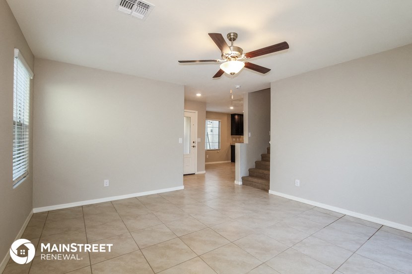 a spacious living room with tile flooring and a ceiling fan