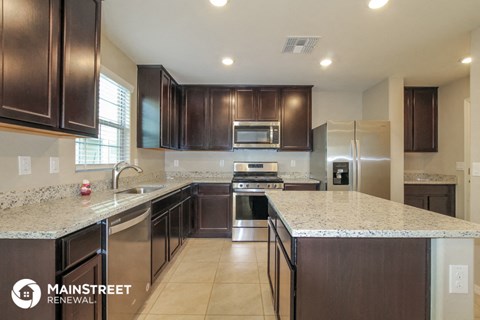 a large kitchen with marble counter tops and dark wood cabinets