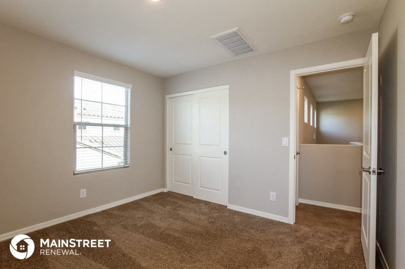 a bedroom with a door to a closet and a window