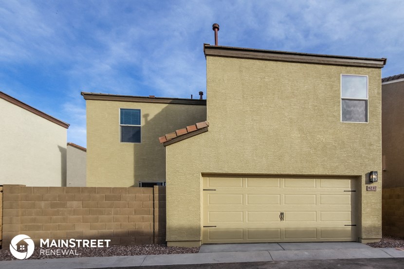 the front of a tan house with a garage door
